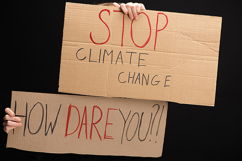 Cropped view of woman with placards with stop climate change and how dare you lettering isolated on black, global warming concept