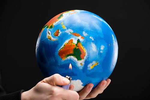 Cropped view of woman holding lighter and globe isolated on black, global warming concept