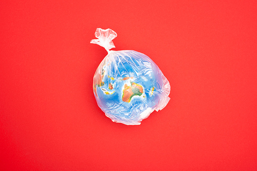 Top view of globe in plastic bag isolated on red, global warming concept
