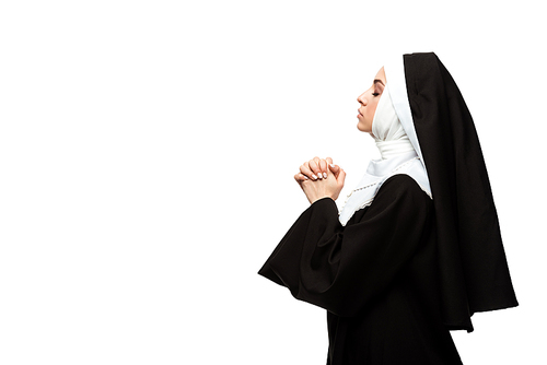 attractive nun praying with closed eyes and hands together isolated on white