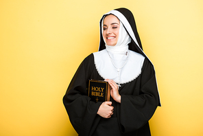 beautiful happy nun holding holy bible on grey