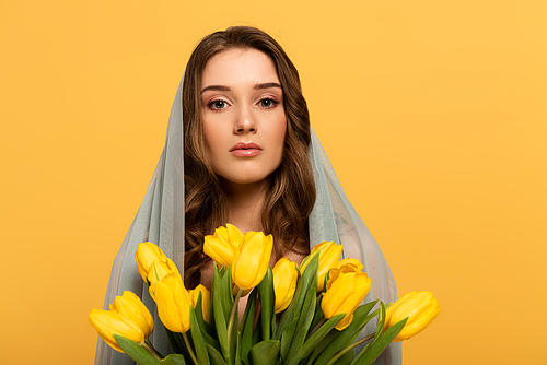 attractive young woman in veil holding bouquet of tulips isolated on yellow