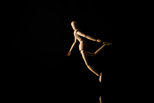 Wooden doll in falling position on black