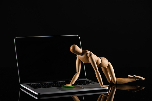 Wooden doll on all four position imitating dusting laptop on black background
