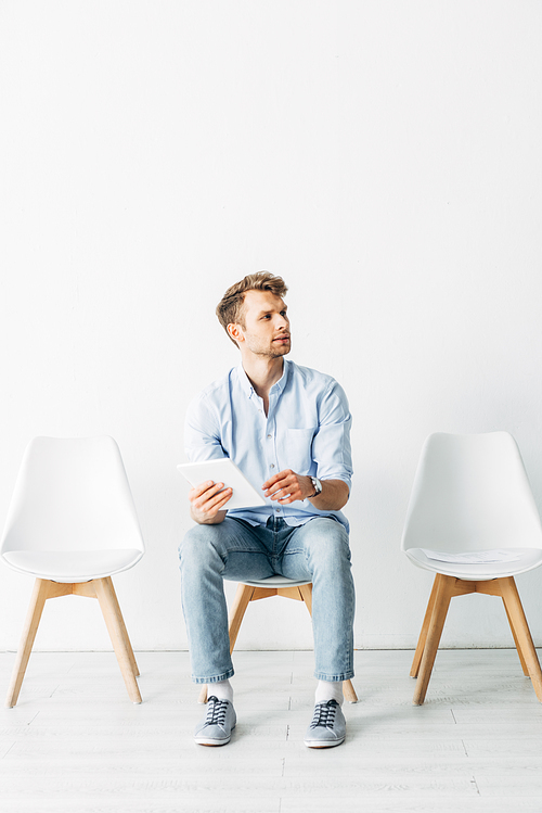 Handsome employee using digital tablet while waiting for job interview