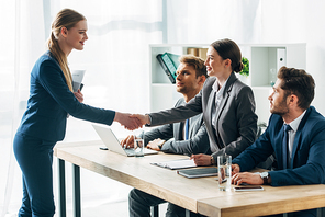 Smiling employee shaking hands with recruiter in office