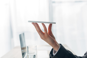 Cropped view of woman holding smartphone near glass of water on table