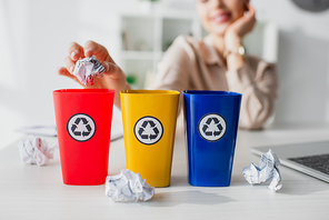 cropped view of businesswoman throwing crumpled papers into recycling buckets  in office