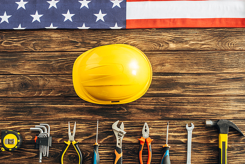 top view of metallic tools, safety helmet and american flag on wooden surface, labor day concept