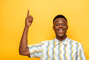 happy african american man pointing with finger up on yellow background
