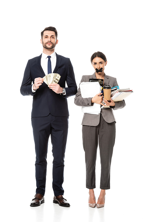 handsome businessman holding dollars near businesswoman with duct tape on mouth on white, sexism concept