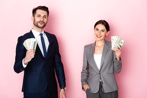 cheerful businessman and businesswoman holding dollar banknotes on pink, gender equality concept