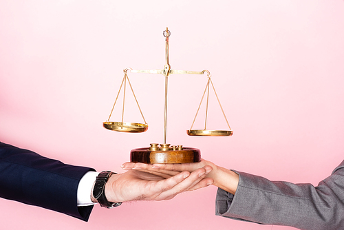cropped view of businessman and businesswoman holding golden scales isolated on pink, gender equality concept