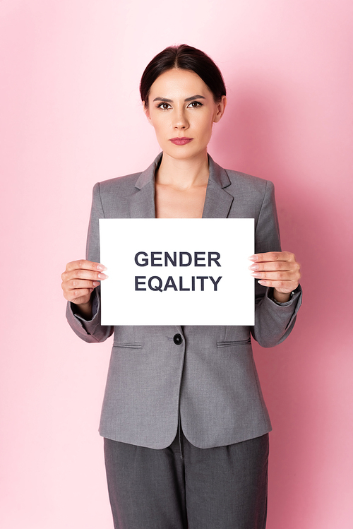 businesswoman holding placard with gender equality lettering on pink