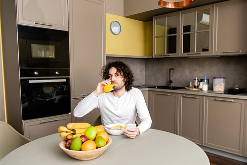 handsome man  while drinking orange juice and using smartphone during breakfast