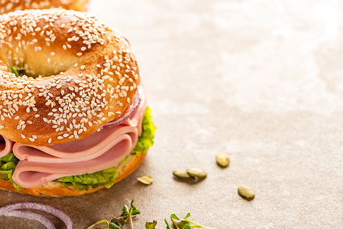 fresh delicious bagel with sausage on textured surface with pumpkin seeds