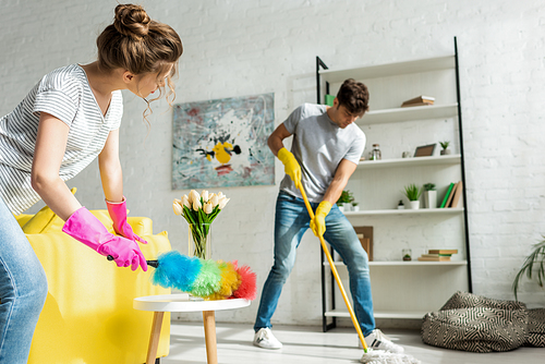 selective focus of man and woman doing spring cleaning in apartment