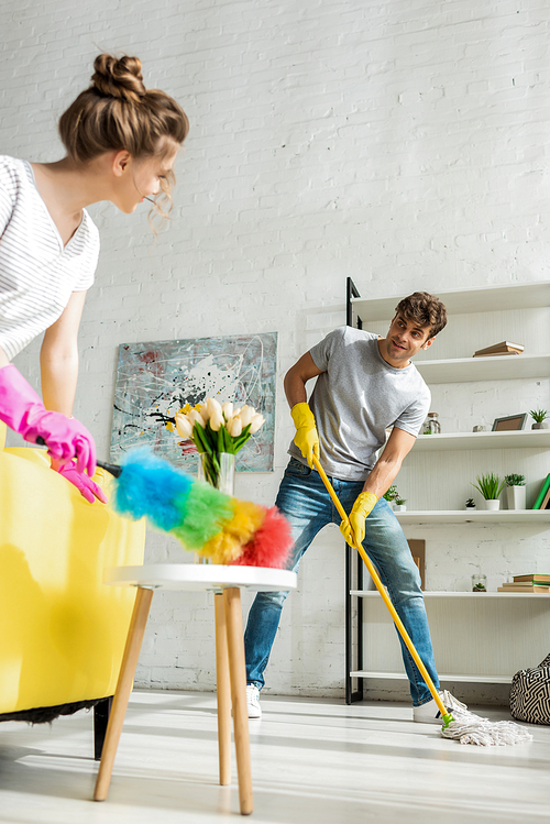selective focus of handsome man and young woman doing spring cleaning in apartment