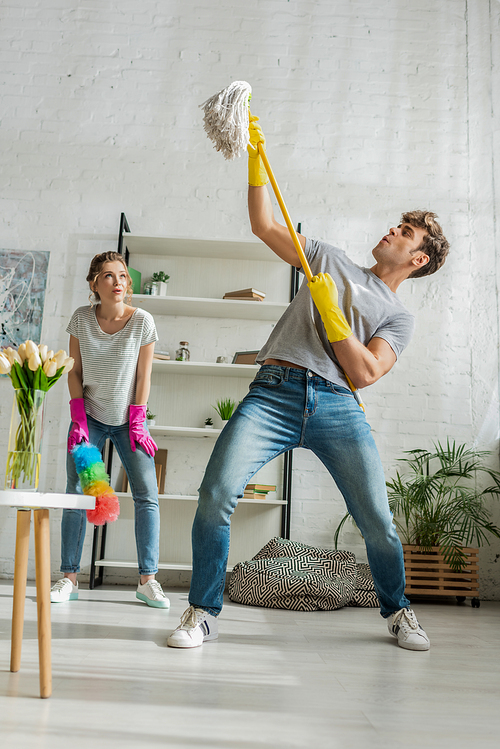 young and surprised woman looking at handsome man with mop