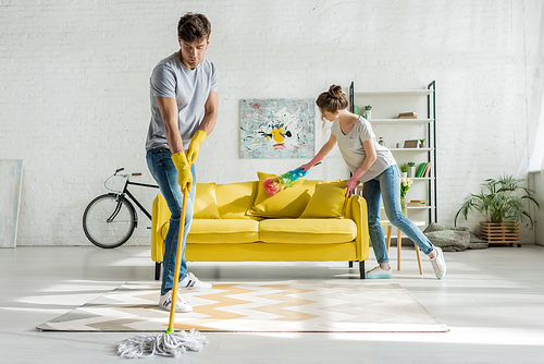 man and woman doing spring cleaning in living room