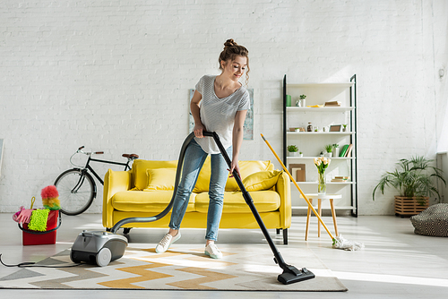 happy girl cleaning carpet with vacuum cleaner