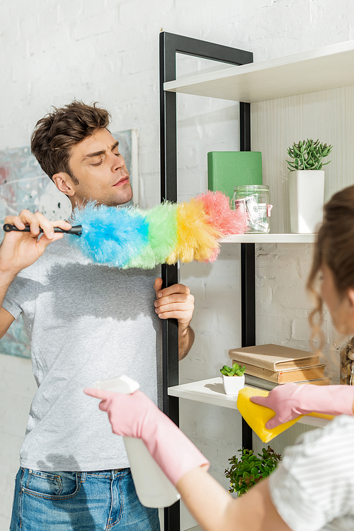 selective focus of handsome man cleaning shelve near girl
