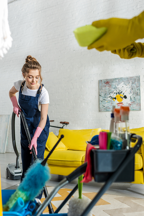 selective focus of attractive cleaner using vacuum cleaner near coworker with sponge