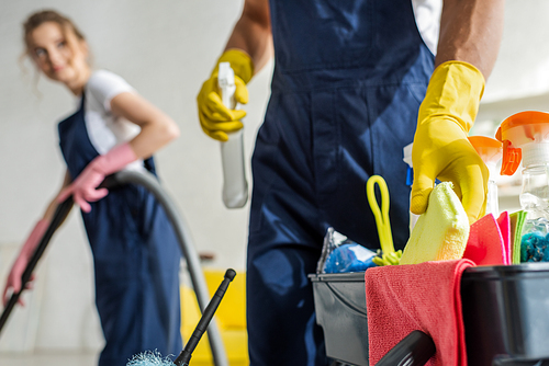 selective focus of cleaner taking sponge while standing near cleaning trolley