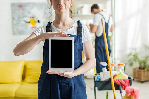 cropped view of smiling cleaner holding digital tablet with blank screen