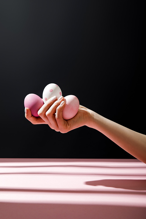 Cropped view of woman holding chicken eggs isolated on black background