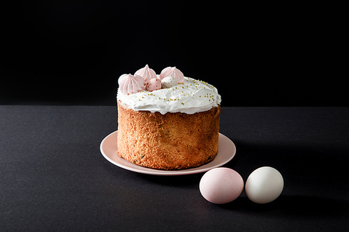 Easter cake and chicken eggs on grey and black