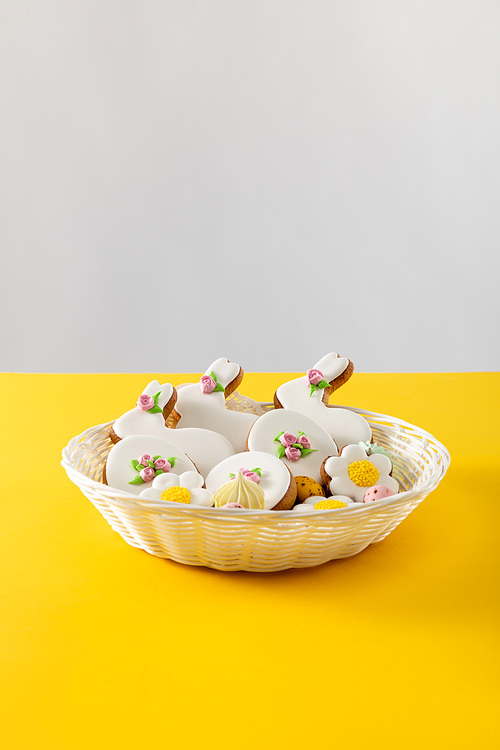 Delicious cookies in wicker basket isolated on grey and yellow