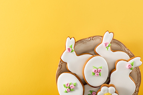 Top view of bowl with delicious easter cookies on yellow background