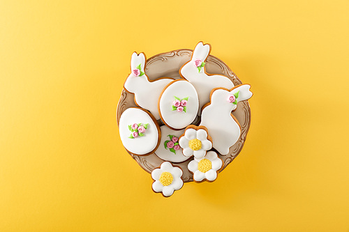 Top view of bowl with tasty easter cookies on yellow background