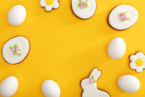 Top view of tasty easter cookies and chicken eggs on yellow
