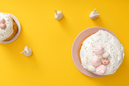 Top view of easter cakes with decorative bunnies on yellow background