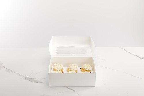 Tasty cupcakes in box isolated on grey