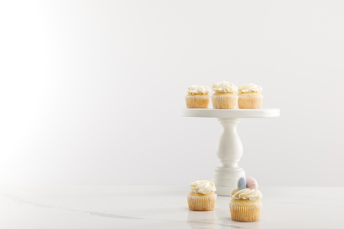 Tasty easter cupcakes on cake stand isolated on grey