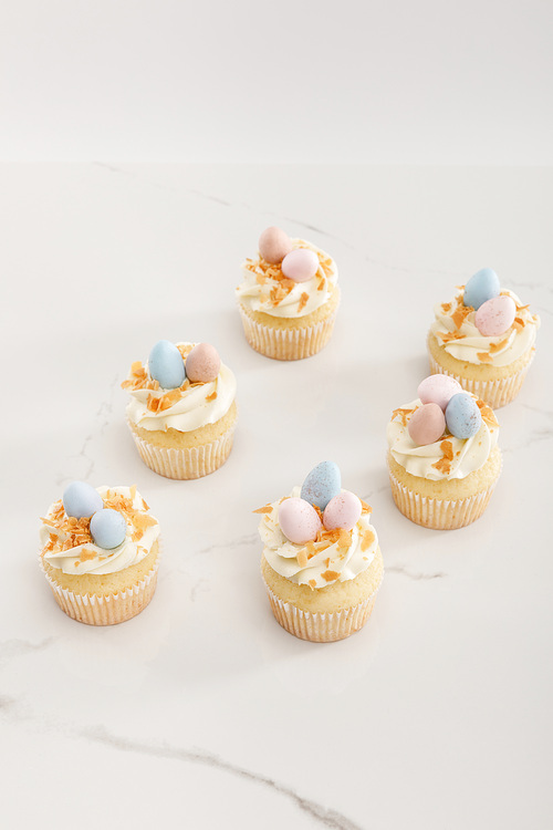 Delicious easter cupcakes with painted quail eggs on top on white background