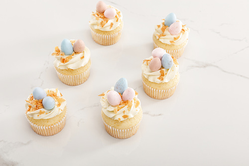 Delicious easter cupcakes with colorful quail eggs on top on white background