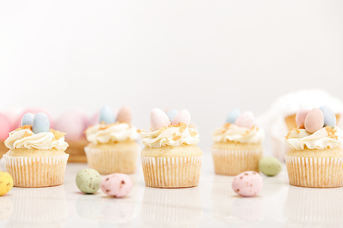 Selective focus of easter cupcakes with painted quail eggs on grey background