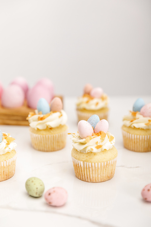 Selective focus of delicious easter cupcakes with painted quail eggs on grey background
