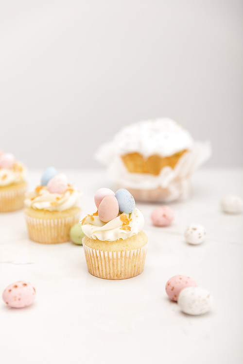 Selective focus of delicious cupcakes with painted quail eggs and easter bread on grey background