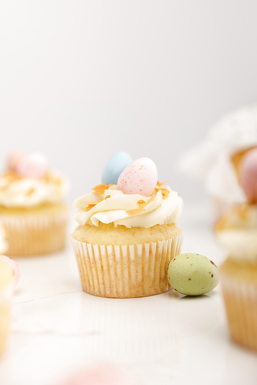 Selective focus of delicious easter cupcakes with colorful quail eggs on grey