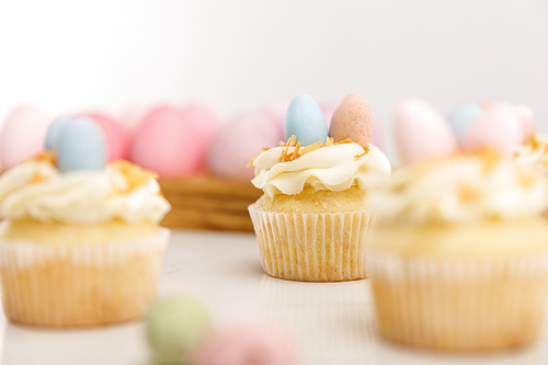 selective focus of delicious cupcakes with . eggs on wooden board on grey background