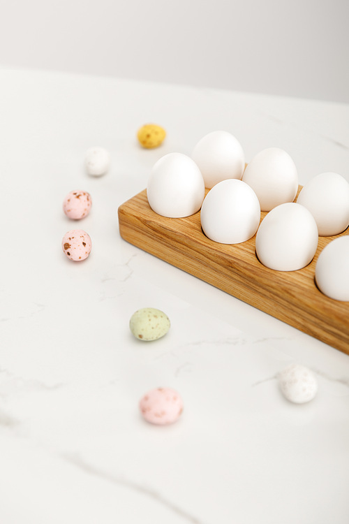 Selective focus of colorful quail and chicken eggs on wooden board on white background