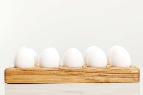 Wooden board with chicken eggs on white background