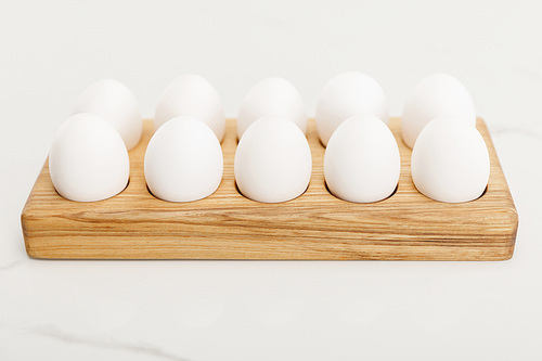 Wooden egg tray with chicken eggs on white background