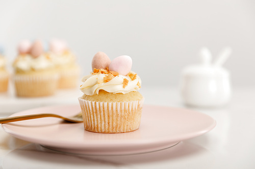 Selective focus of cupcake on plate with fork on grey background