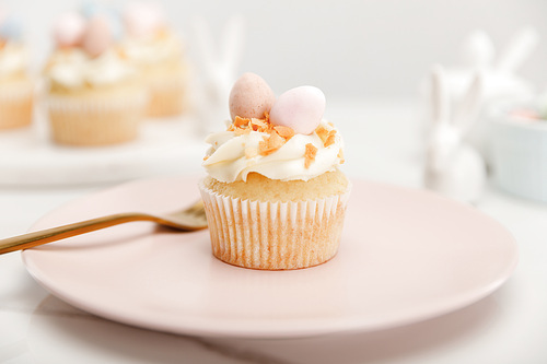 Selective focus of cupcake on plate with fork on grey background